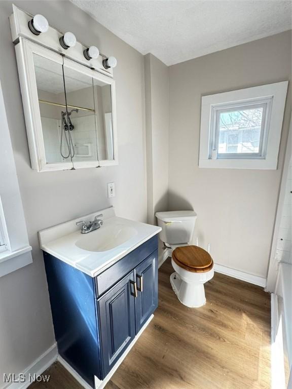 2106 17th St SW, Akron, OH 44314 - full bathroom featuring vanity, toilet, baseboards, a textured ceiling, and wood finished floors