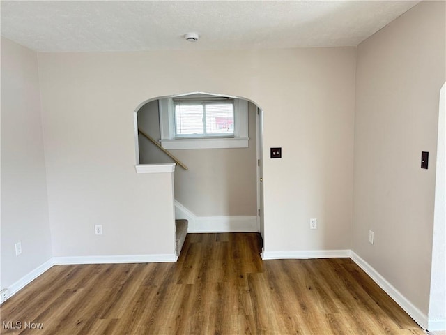 2106 17th St SW, Akron, OH 44314 - unfurnished room featuring baseboards, wood finished floors, arched walkways, and stairs