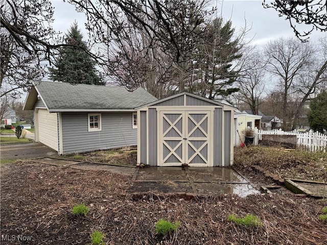 view of shed with driveway, fence, and a garage