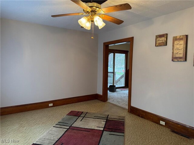 carpeted spare room featuring baseboards, ceiling fan, and visible vents