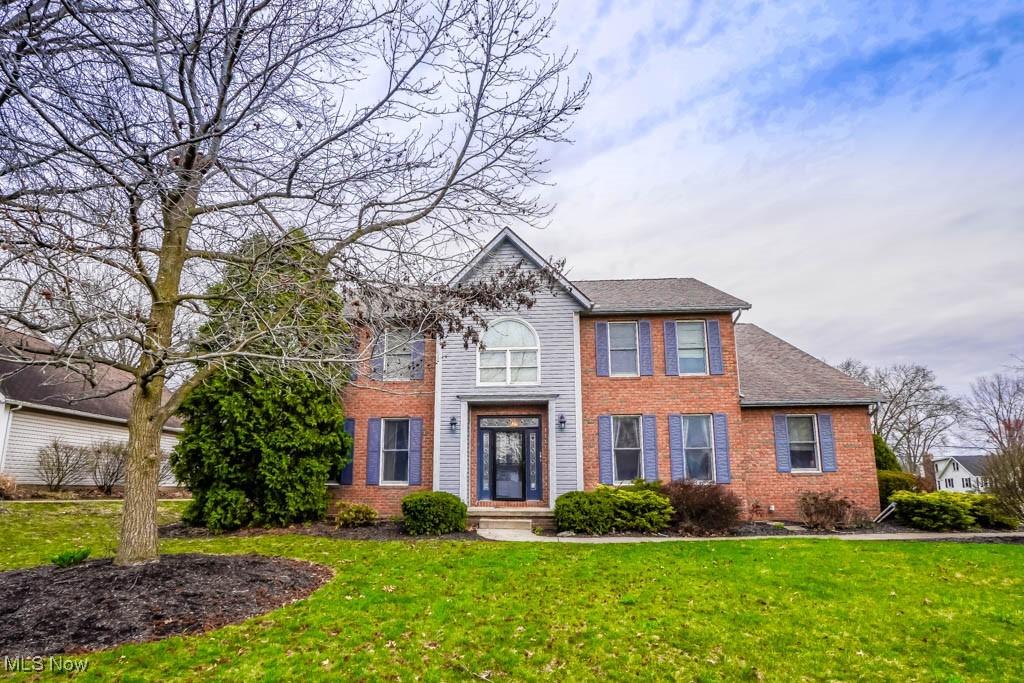 colonial home featuring brick siding and a front yard