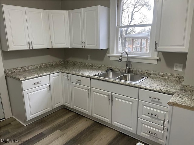 kitchen with a sink, light countertops, white cabinetry, and dark wood-style floors