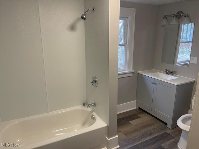 full bathroom featuring washtub / shower combination, baseboards, toilet, vanity, and wood finished floors