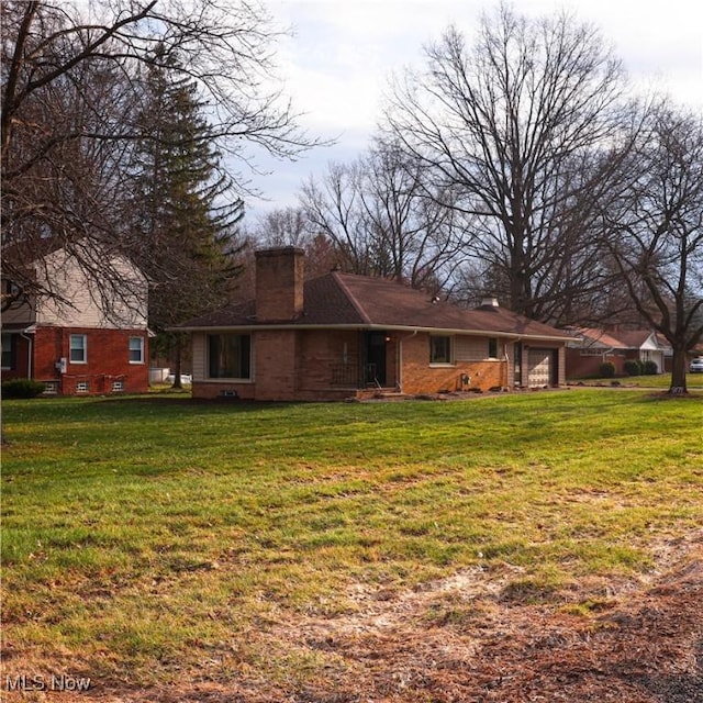 9171 Ridge Rd, North Royalton, OH 44133 - back of property with a chimney, brick siding, a garage, and a lawn