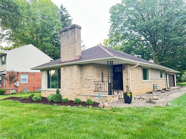 9171 Ridge Rd, North Royalton, OH 44133 - view of side of property with a chimney, brick siding, a lawn, and a garage