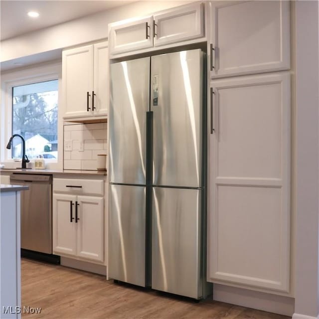 9171 Ridge Rd, North Royalton, OH 44133 - kitchen featuring stainless steel appliances, white cabinetry, light wood-type flooring, decorative backsplash, and recessed lighting