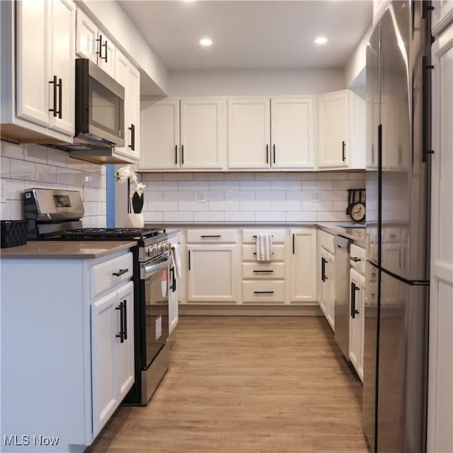 9171 Ridge Rd, North Royalton, OH 44133 - kitchen with stainless steel appliances, white cabinets, decorative backsplash, light wood finished floors, and recessed lighting