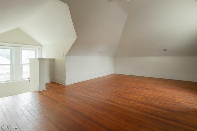 bonus room featuring baseboards, vaulted ceiling, and hardwood / wood-style flooring