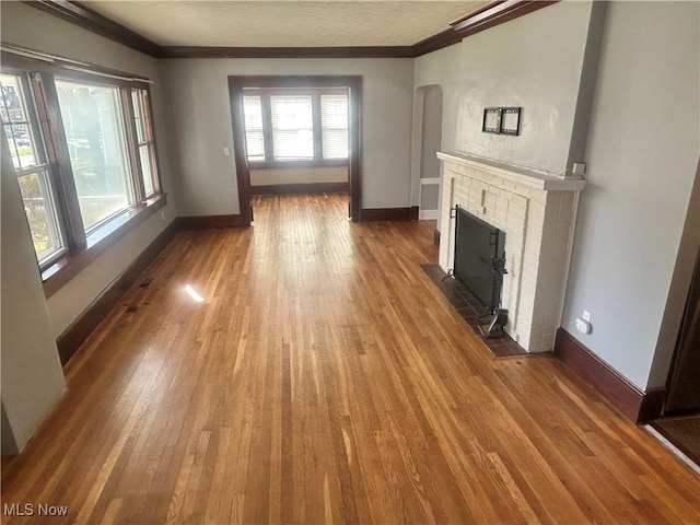 unfurnished living room with wood-type flooring, ornamental molding, and baseboards