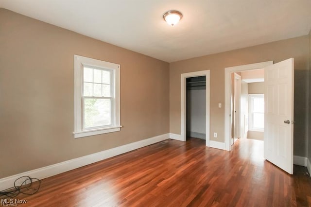 unfurnished bedroom with dark wood-type flooring, baseboards, and a closet