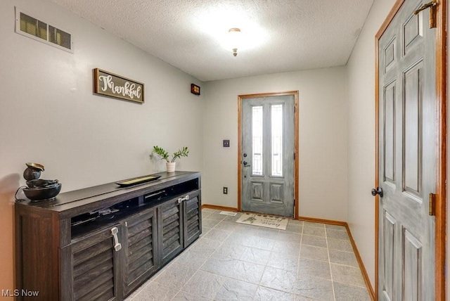 entryway featuring a textured ceiling, baseboards, and visible vents
