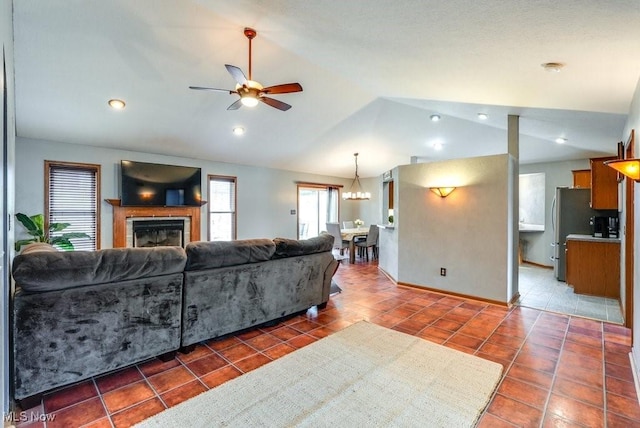 living area with a tile fireplace, baseboards, tile patterned floors, ceiling fan with notable chandelier, and vaulted ceiling