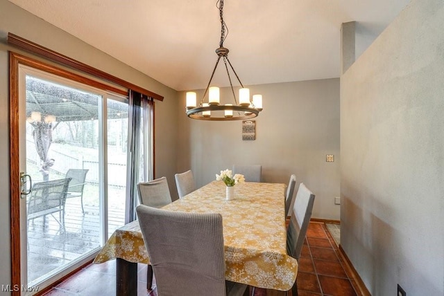 dining area featuring baseboards, lofted ceiling, dark tile patterned floors, and an inviting chandelier