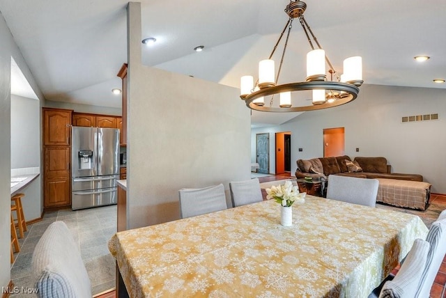 dining space with vaulted ceiling, a chandelier, and visible vents
