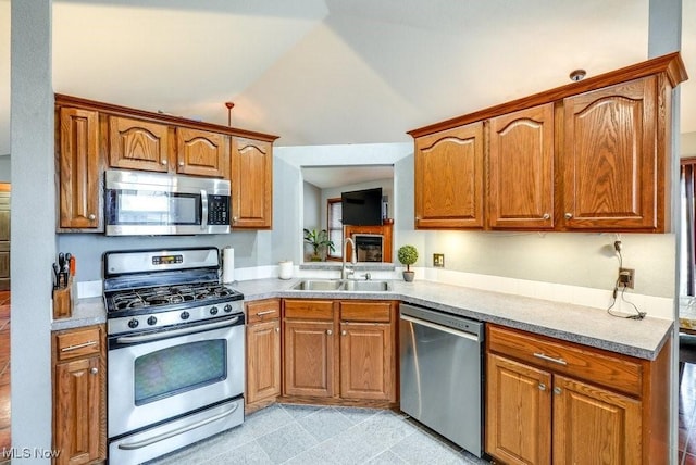 kitchen with light countertops, a sink, appliances with stainless steel finishes, lofted ceiling, and brown cabinetry