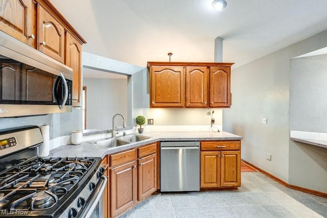 kitchen featuring brown cabinets, light countertops, a sink, and stainless steel appliances