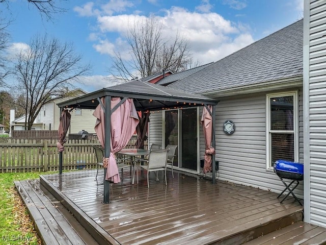 wooden terrace with fence, outdoor dining area, and a gazebo