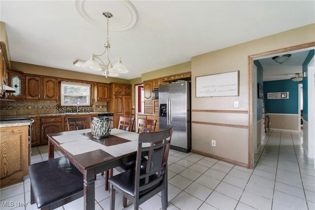 dining area with an inviting chandelier, light tile patterned floors, and baseboards