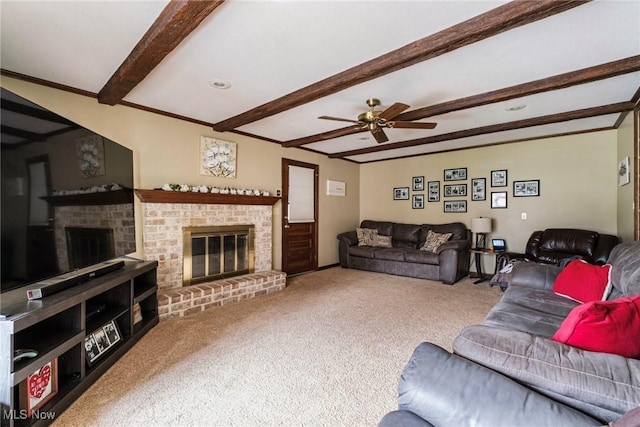 carpeted living room featuring ceiling fan, ornamental molding, a fireplace, and beam ceiling