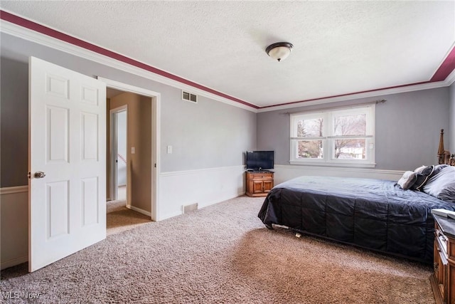 carpeted bedroom featuring crown molding, a textured ceiling, and visible vents