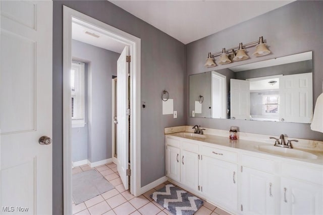 bathroom featuring tile patterned flooring, a sink, baseboards, and double vanity
