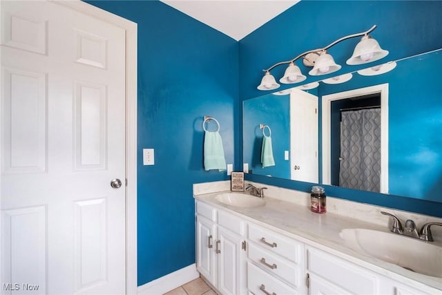 bathroom featuring a sink, tile patterned floors, baseboards, and double vanity