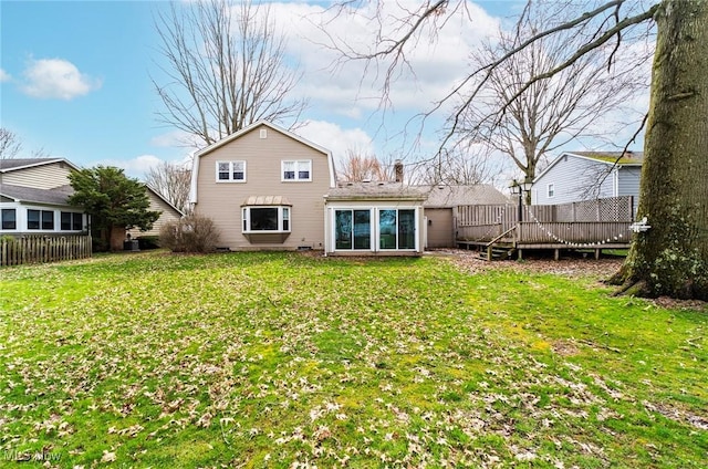 rear view of house featuring a lawn, a deck, fence, and a chimney