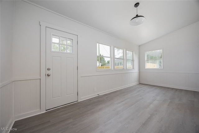foyer entrance with wood finished floors, wainscoting, and lofted ceiling