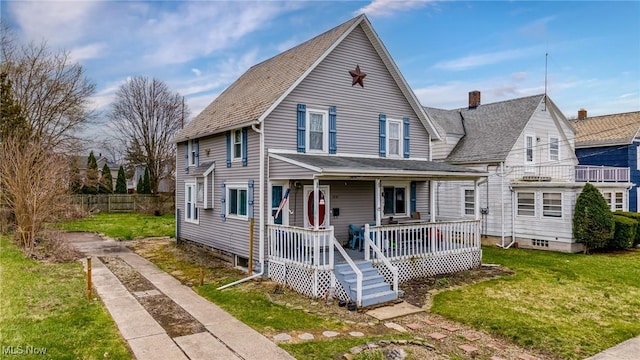 view of front facade featuring driveway, a front yard, covered porch, roof with shingles, and a chimney
