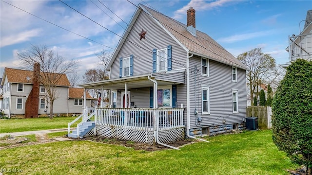 exterior space with central air condition unit, fence, a chimney, covered porch, and a yard