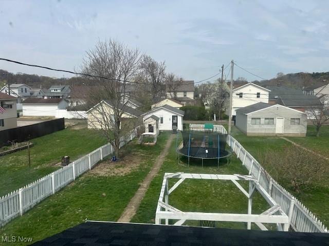 view of yard featuring a fenced backyard, a residential view, and a trampoline