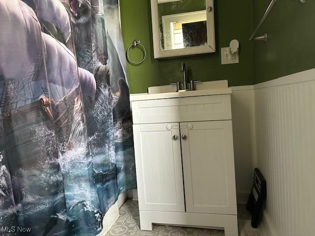 full bath with a shower with curtain, vanity, and wainscoting