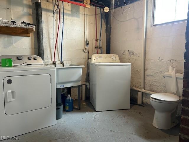 clothes washing area featuring washing machine and clothes dryer, a sink, and laundry area