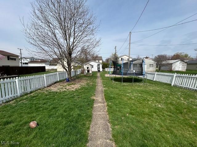 view of yard with a fenced backyard, a residential view, and a trampoline