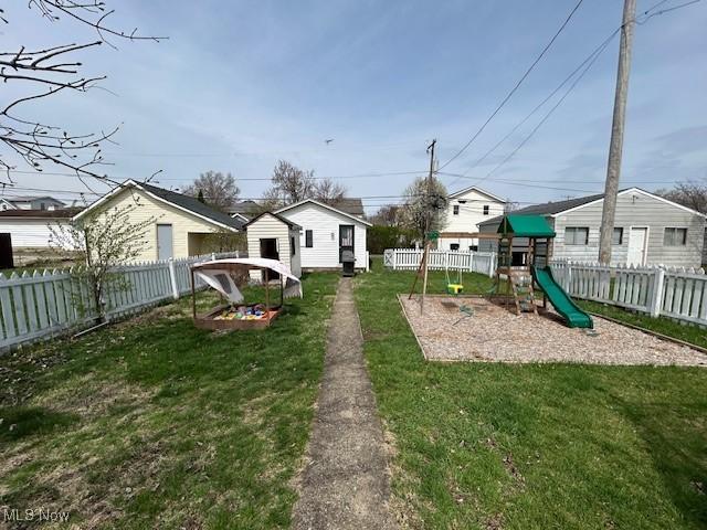 view of yard with a fenced backyard, an outdoor structure, and a playground