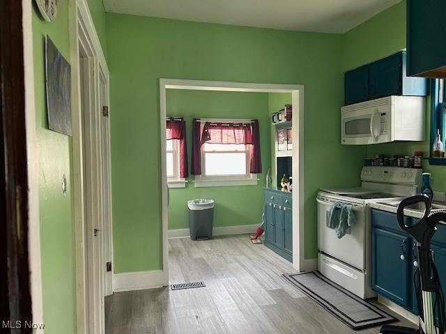 kitchen with baseboards, light wood-style floors, white appliances, blue cabinetry, and light countertops