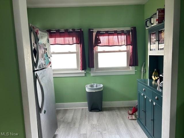 laundry room with light wood-style floors, stacked washer and dryer, baseboards, and laundry area