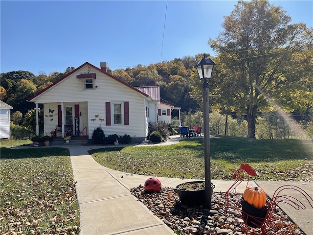 23314 Frostyville Rd, Caldwell, OH 43724 - bungalow-style house with a chimney, metal roof, and a front lawn