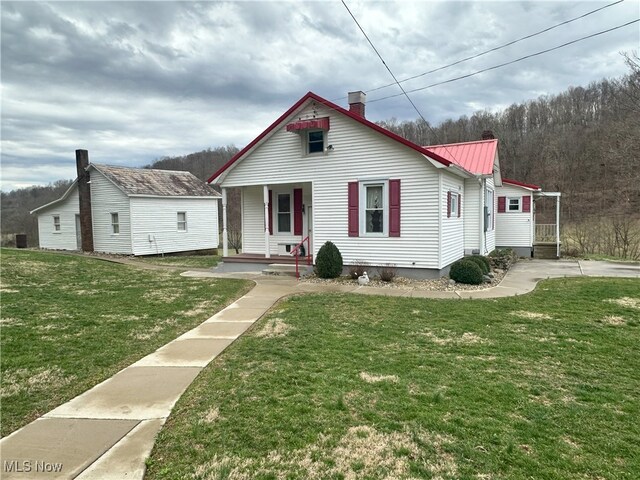 23314 Frostyville Rd, Caldwell, OH 43724 - view of front of house featuring a chimney, metal roof, covered porch, and a front yard