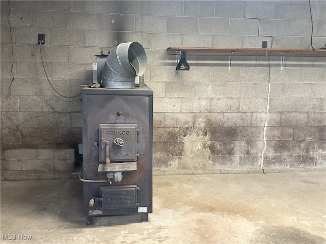 23314 Frostyville Rd, Caldwell, OH 43724 - interior details featuring unfinished concrete floors, concrete block wall, and a wood stove