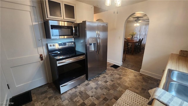 228 N 8th St, Coshocton, OH 43812 - kitchen featuring baseboards, a ceiling fan, appliances with stainless steel finishes, arched walkways, and a sink