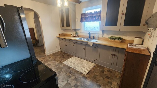 228 N 8th St, Coshocton, OH 43812 - kitchen with baseboards, black / electric stove, arched walkways, a sink, and gray cabinets