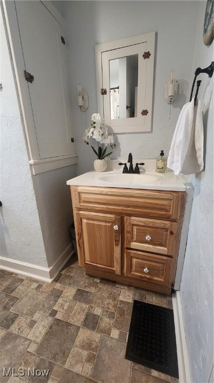 228 N 8th St, Coshocton, OH 43812 - bathroom featuring baseboards, stone finish floor, and vanity
