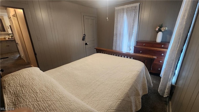 228 N 8th St, Coshocton, OH 43812 - bedroom featuring connected bathroom, dark colored carpet, and wood walls
