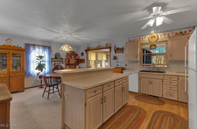 kitchen featuring light countertops, ceiling fan, a kitchen island, a sink, and white dishwasher