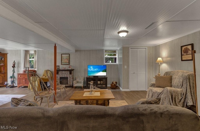 living area featuring a fireplace, visible vents, wood finished floors, and ornamental molding
