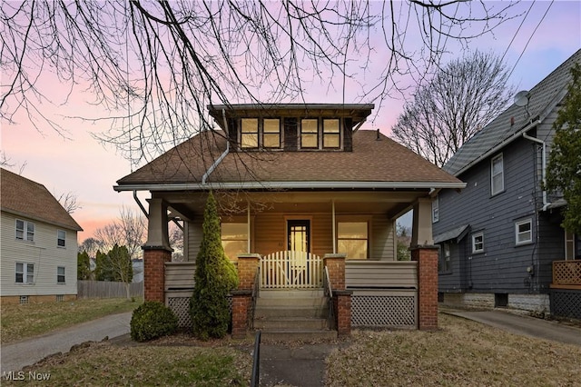 bungalow with covered porch and roof with shingles