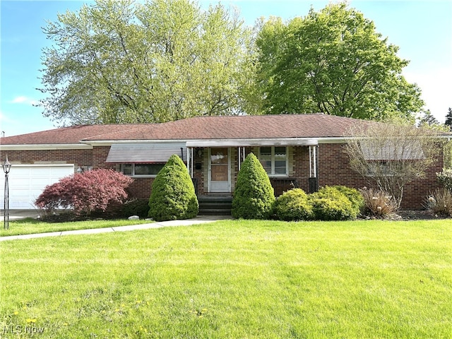 single story home with brick siding, an attached garage, and a front yard