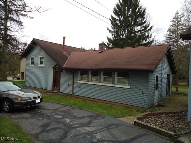 view of front facade featuring a chimney and driveway