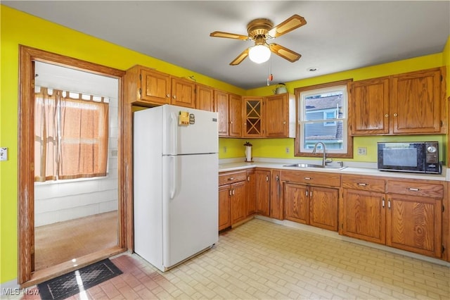 kitchen featuring light countertops, visible vents, a sink, black microwave, and freestanding refrigerator